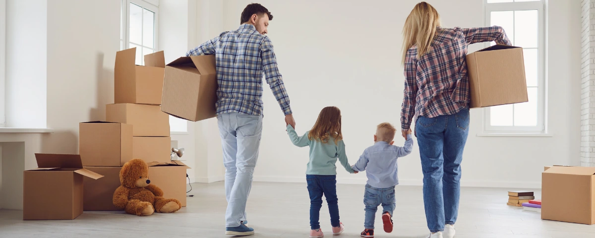 A family walking into a new home with moving boxes, symbolizing the successful result of using a professional realtor to set the right listing price.