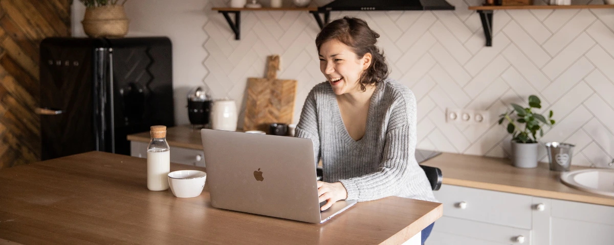 A homeowner using a laptop in her kitchen to check Zillow Zestimates and online property data.