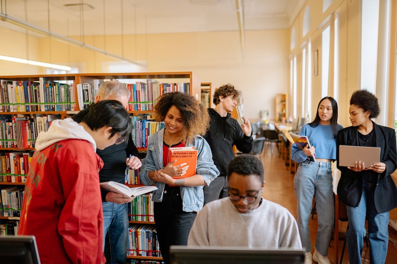 college students in a library with their professor